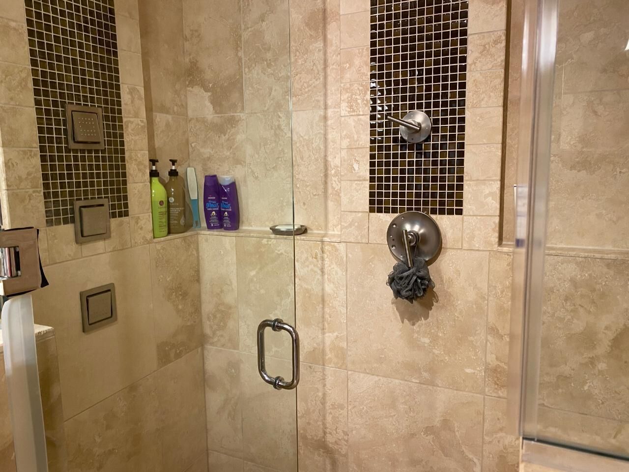 A shower area with tiled walls, a glass door, and a towel rack.