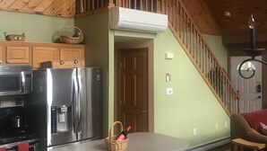 A kitchen with a wooden staircase, a refrigerator, a microwave, and a dining area with chairs. - Windham Mountain Chalet with Treehouse sleeps 15, Game Room & fireplace (Windham)