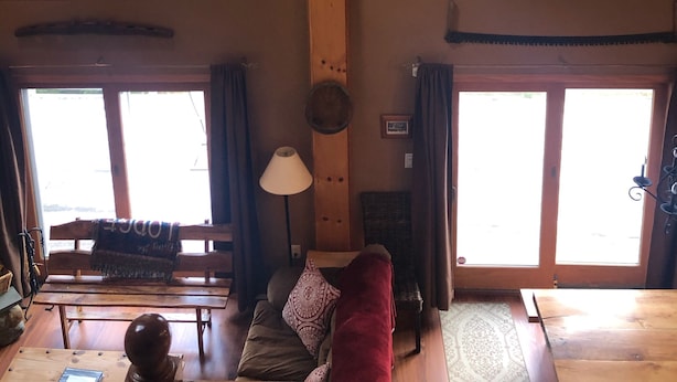 A spacious room with high ceilings and large windows, a wooden bench, a sofa, and a lamp. - Windham Mountain Chalet with Treehouse sleeps 15, Game Room & fireplace (Windham)