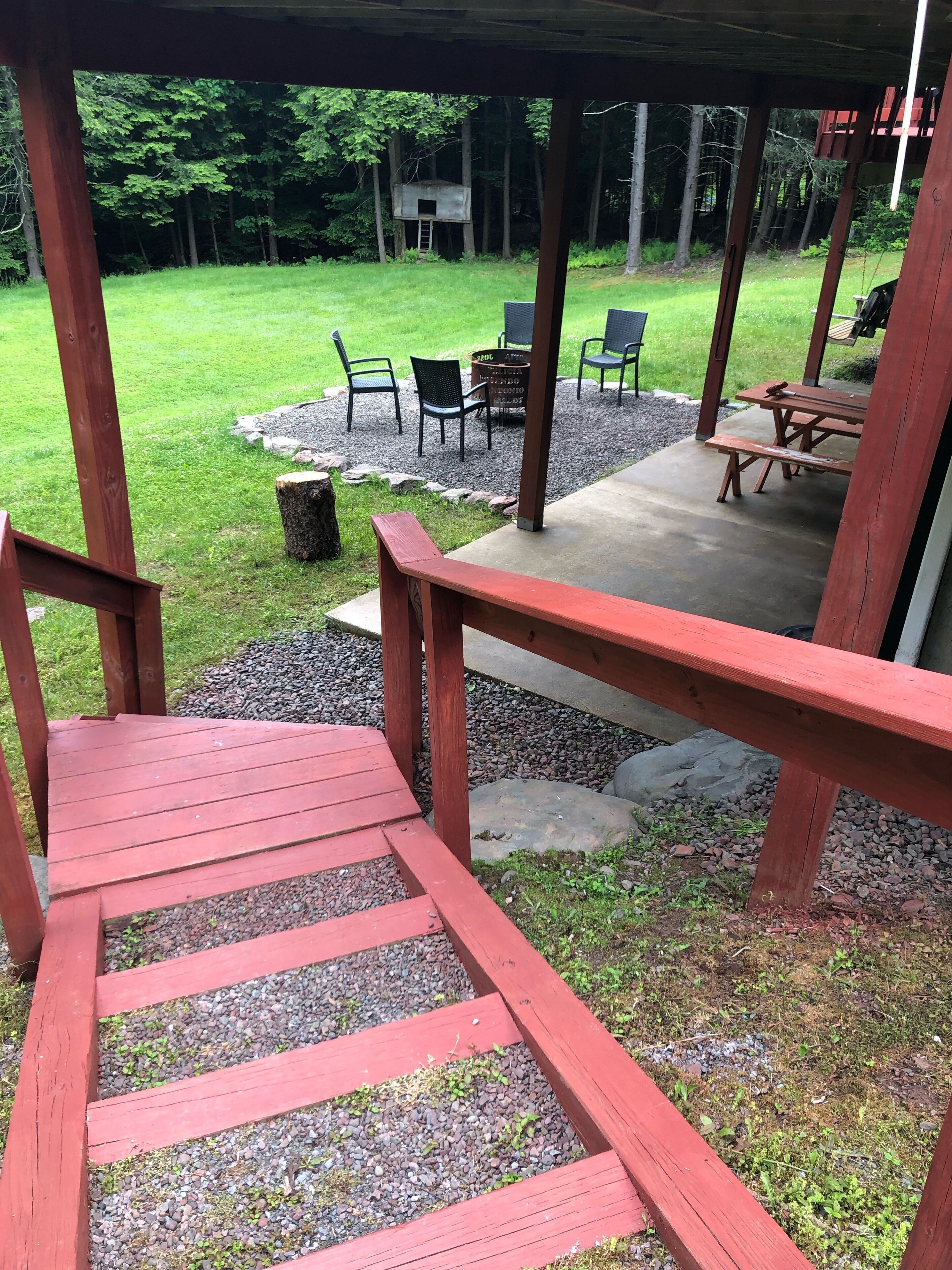 A wooden deck with a red railing leading to a covered patio area.