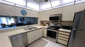A modern kitchen with stainless steel appliances, a double sink, and a microwave. - Just Listed for 2027 Season:  Glen Eagle Golf & Country Club (Naples)