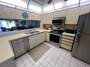 Una cucina moderna con elettrodomestici in acciaio inossidabile, un lavello doppio e un forno a microonde.