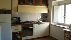Eine kleine Küche mit Kühlschrank, Herd, Backofen und Spüle.