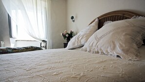 Ein ordentlich bezogenes Bett mit einem gemusterten Überwurf, einem Holzkopfbrett und weißen Kissen.