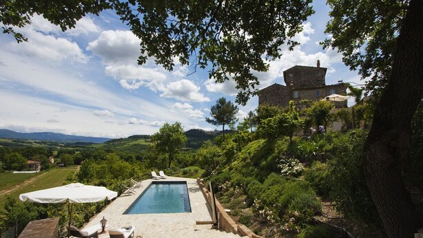 Ein Poolbereich mit Stein-Terrasse, Liegestühlen und Blick auf die Landschaft.