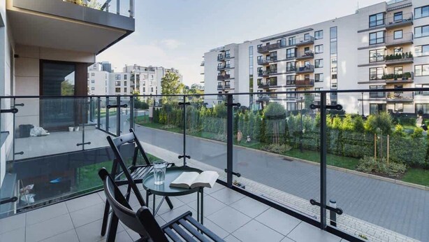 A modern apartment with a balcony, a glass table, and a chair.