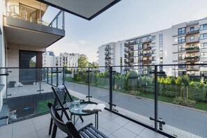 A modern apartment with a balcony, a glass table, and a chair.
