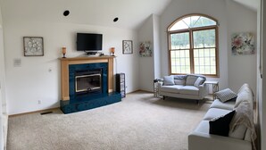 Una sala de estar amplia con chimenea, televisión y un ventanal grande.