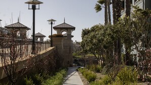 Un chemin bordé de lampadaires et d’un mur de pierre, menant à un bâtiment au style architectural traditionnel.