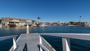 Un port de plaisance avec des bateaux amarrés, un ciel bleu dégagé et des maisons en arrière-plan.