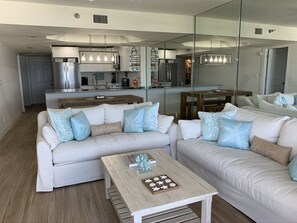 Relax in this inviting living space, featuring a sofa set, coffee table, and kitchen area.