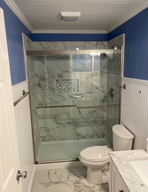 A bathroom with a glass-enclosed shower, a toilet, and marble flooring. - 871 Ketch Court II 1BR 1BA 1ST Floor Walk-In Shower Patio Pool Gas Grill (Hilton Head Island)