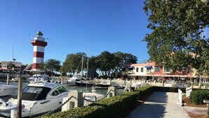 Un puerto deportivo con barcos amarrados, un faro y edificios al fondo.