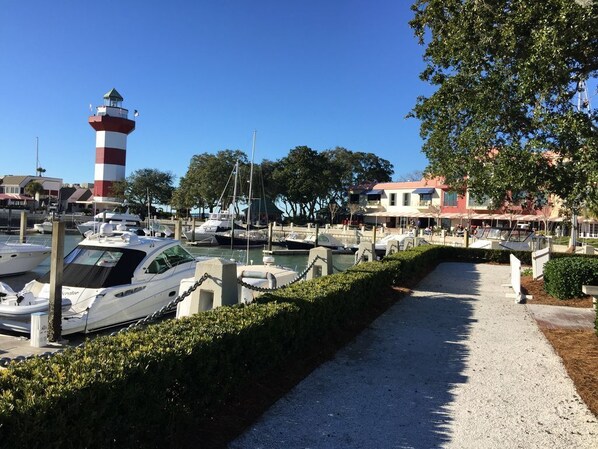 Un puerto deportivo con barcos amarrados, un faro y edificios al fondo.