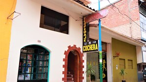 A building with a storefront labeled "COCHERA" and a sign above it reading "SPEDAJES." - Hospedaje Don Juan (Cusco)