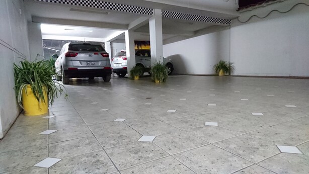 A parking garage with tiled floors and potted plants. - Hospedaje Don Juan (Cusco)