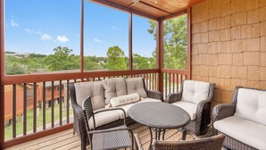 Un espacio de estar al aire libre techado, con mobiliario de mimbre y vistas del paisaje circundante.