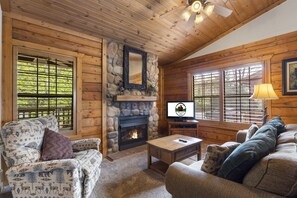 Cozy cabin-style room with a fireplace, TV, and comfortable seating.