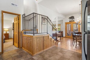 Staircase leads to a dining area with a table and chairs, offering a view of the outdoors.