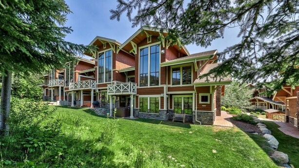 A multi-story lodge with a prominent central tower, large windows, and a well-maintained lawn. - Dog-friendly, 3 bedroom ski-in/ski-out end unit (Sun Peaks)