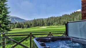 A hot tub with a view of a golf course and a mountain. - Dog-friendly, 3 bedroom ski-in/ski-out end unit (Sun Peaks)