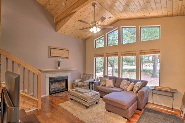A spacious living room with a fireplace, wooden ceiling, large windows, and a cozy seating area. - Forest-View Retreat in Payson, Close to Hiking! (Payson)
