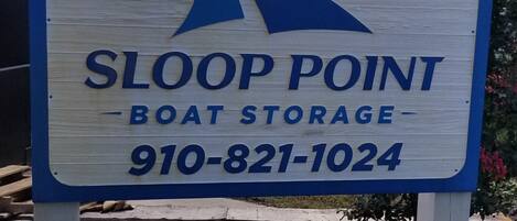 Señal de Sloop Point Boat Storage, número de contacto 910-821-1024.