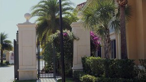 A gated entrance with palm trees and a building facade. - Warmth and harmony await you. (Bonita Springs)