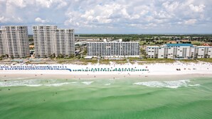 Un resort costero con edificios altos, una playa de arena y aguas turquesas cristalinas.