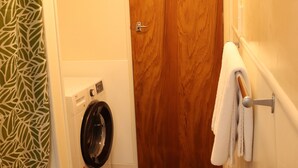 Una lavanderia con una lavatrice, una porta in legno e un porta asciugamani.