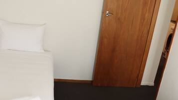 Una habitación de hotel con dos camas, una puerta de madera y un cuadro de un perro con gafas.