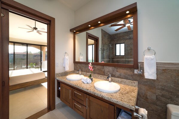 Une salle de bain moderne avec deux lavabos, un grand miroir et un ventilateur de plafond.