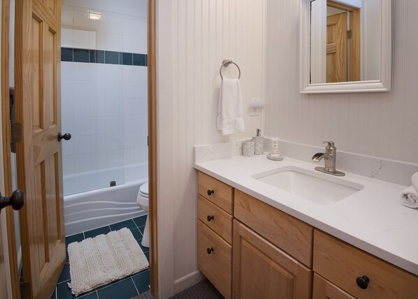 A bathroom with a bathtub, toilet, sink, and wooden cabinets.