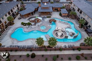 An aerial view of a hotel with multiple swimming pools, lounge areas, and a landscaped courtyard.