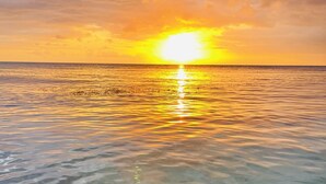 A sunset over a calm sea with clear water reflecting the sky. - VistaPinero Beach Front Apartment - Joyudas Cabo Rojo (Cabo Rojo)