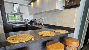 A modern kitchen with a central island, stainless steel appliances, and a built-in oven. - VistaPinero Beach Front Apartment - Joyudas Cabo Rojo (Cabo Rojo)