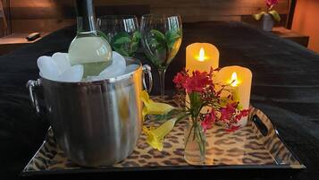 Een dienblad met een metalen beker gevuld met ijs, een fles, twee brandende kaarsen en een vaas met bloemen.