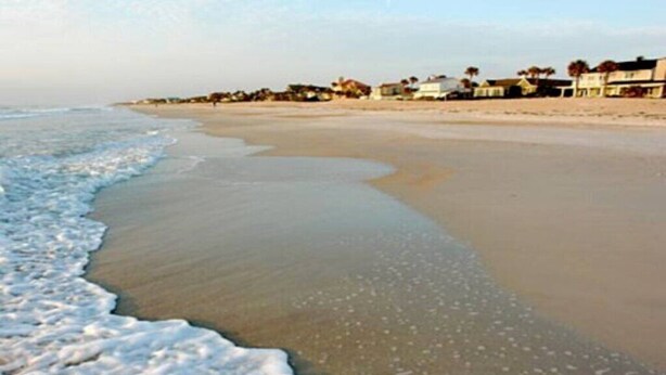 A beach with a sandy shore and a row of houses in the background. -  Private Studio Entry (Ponte Vedra Beach)