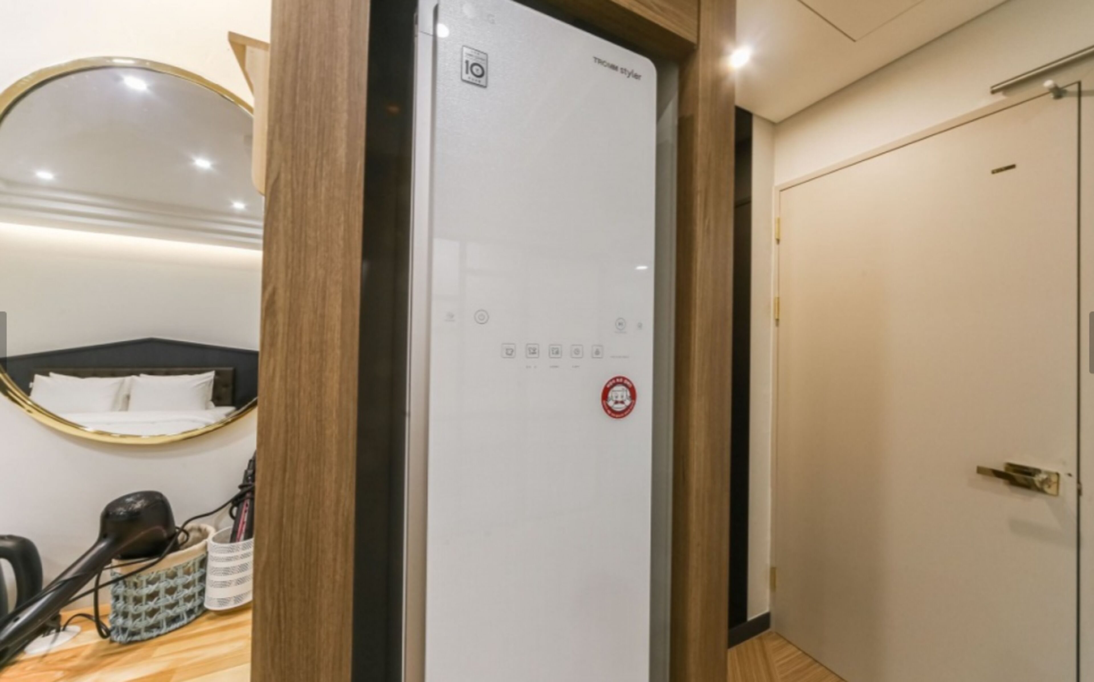 A hotel room with a bed, a mirror, a whiteboard, and a door.