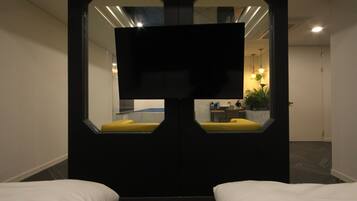Ein Hotelzimmer mit einem großen Spiegel, zwei Betten, einem Fernseher und einem kleinen Schreibtisch mit Stuhl.