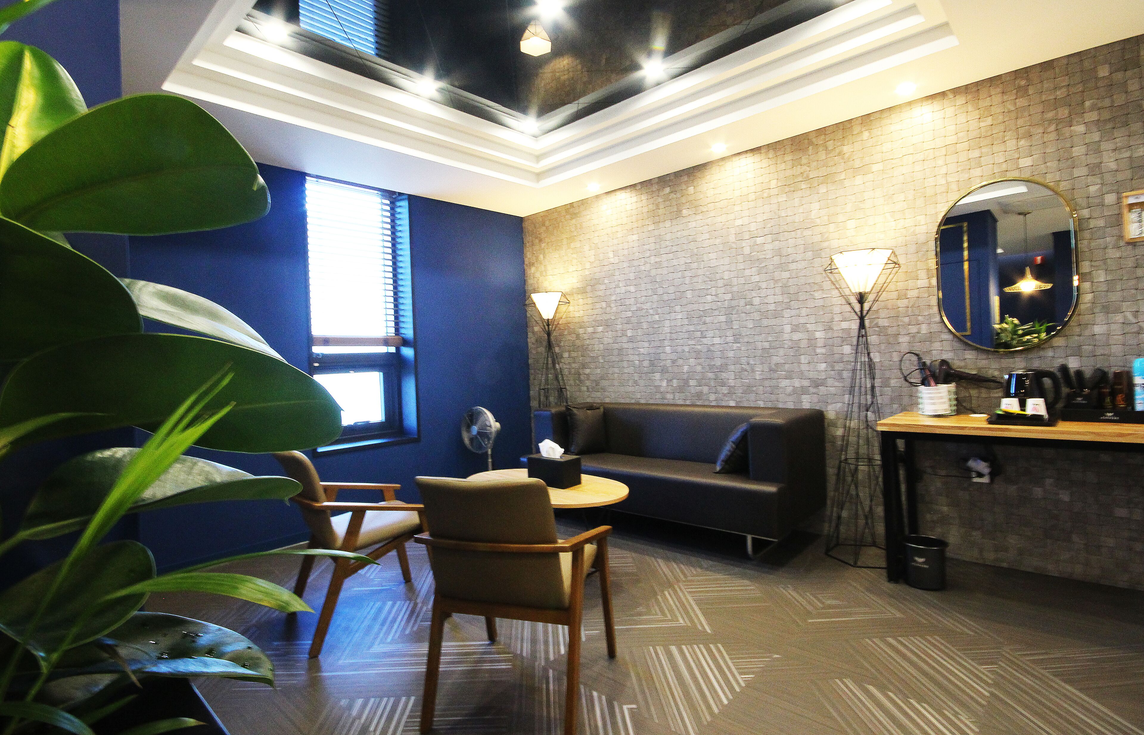 A modern room with a brick wall, a round table, a sofa, and a large mirror.