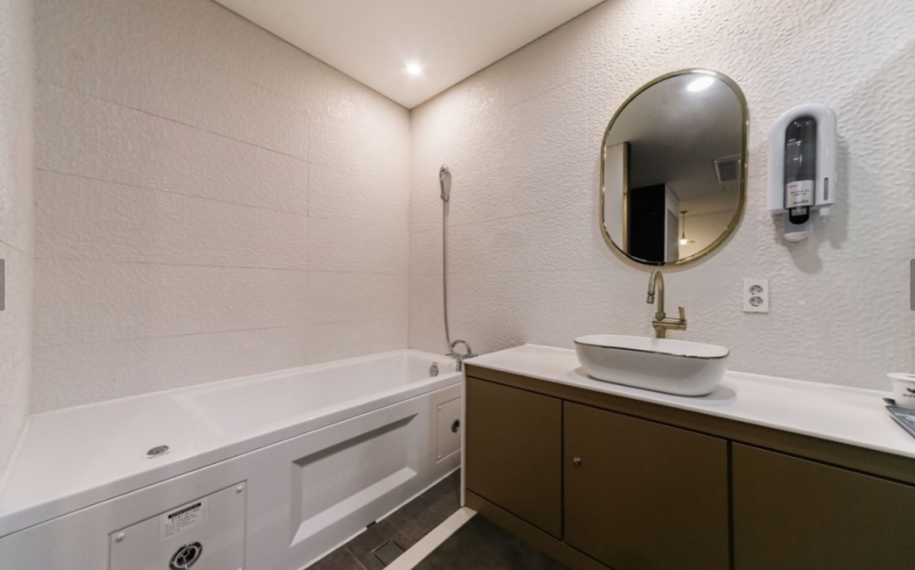 A modern bathroom with a bathtub, a sink, and a mirror.