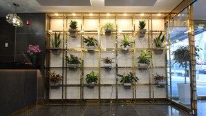 A reception area with a marble wall, potted plants, and a glass door leading outside. - Amare Hotel (Daegu)