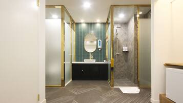 A modern bathroom with a freestanding mirror, a white sink, and a shower enclosure.