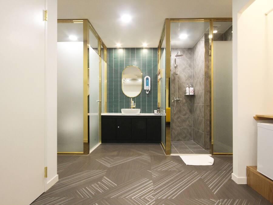 A modern bathroom with a freestanding mirror, a white sink, and a shower enclosure.