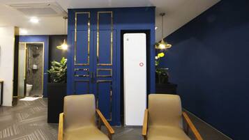 A reception area with two leather chairs, a blue wall with gold trim, a white door, and a potted plant.
