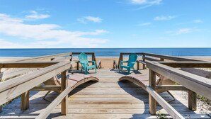 A wooden boardwalk leading to beach chairs facing the ocean.