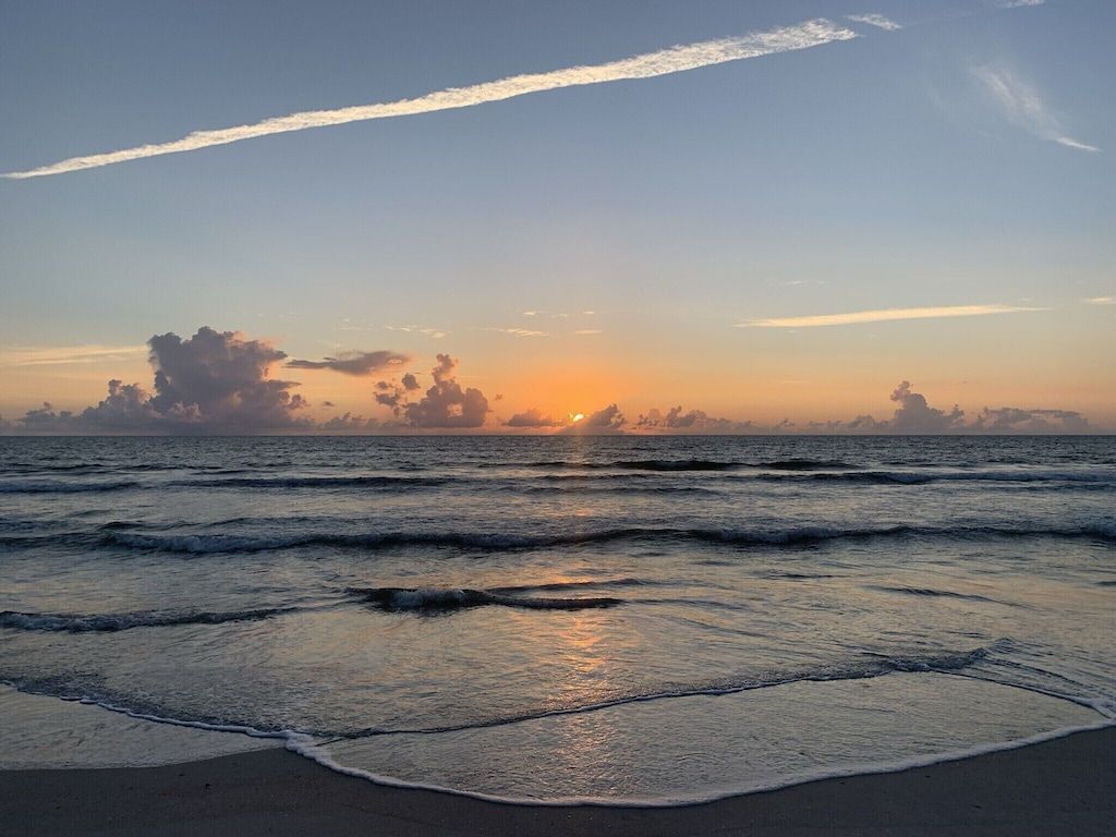 Una playa con olas y un atardecer.