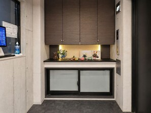 Een moderne keuken met donkere houten kastjes, een aanrecht met diverse spullen, en een matglazen deur.
