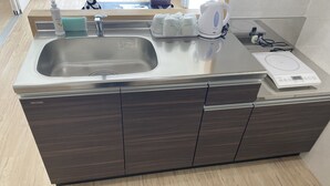 A modern kitchen with a stainless steel sink, a built-in dishwasher, a kettle, and a rice cooker. - HOTEL Ishigakijima 2020 (Ishigaki)